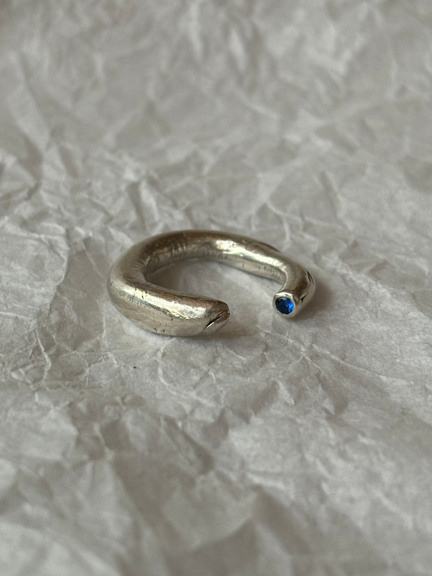 silver ring open and adjustable with a small blue sapphire